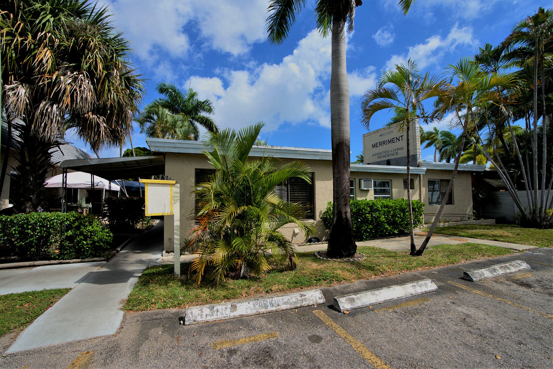 Merriment Assisted Living Residence exterior at 1835 Wilson St, Hollywood, Florida surrounded by palm trees and tropical landscaping